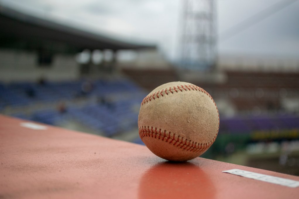 Baseball ball in foreground, pitch in background